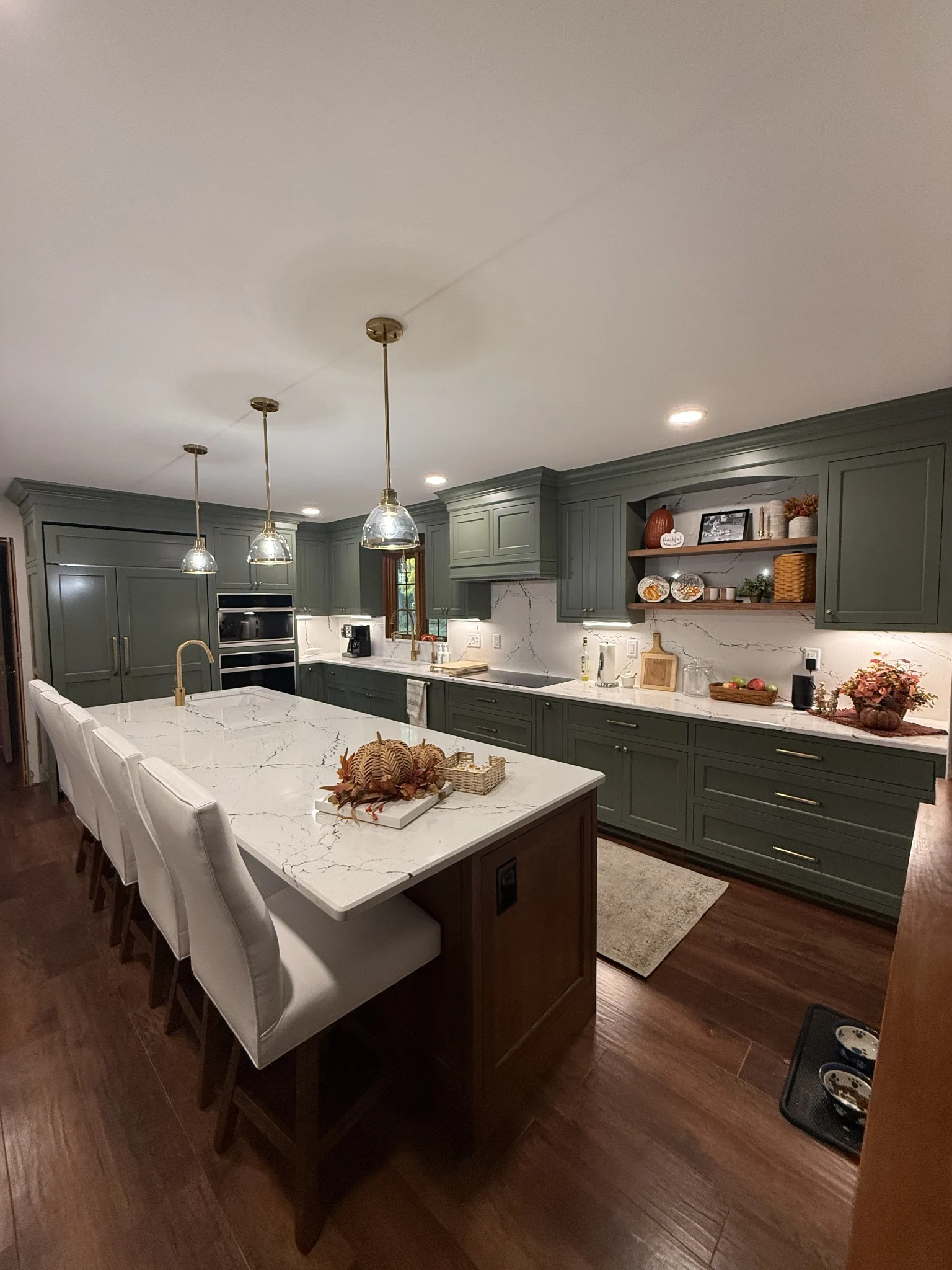 Green kitchen cabinetry, integrated appliances, and a wood island
